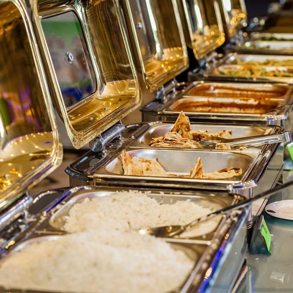 A buffet line with several chafing dishes filled with rice, flatbread, and other hot dishes.
